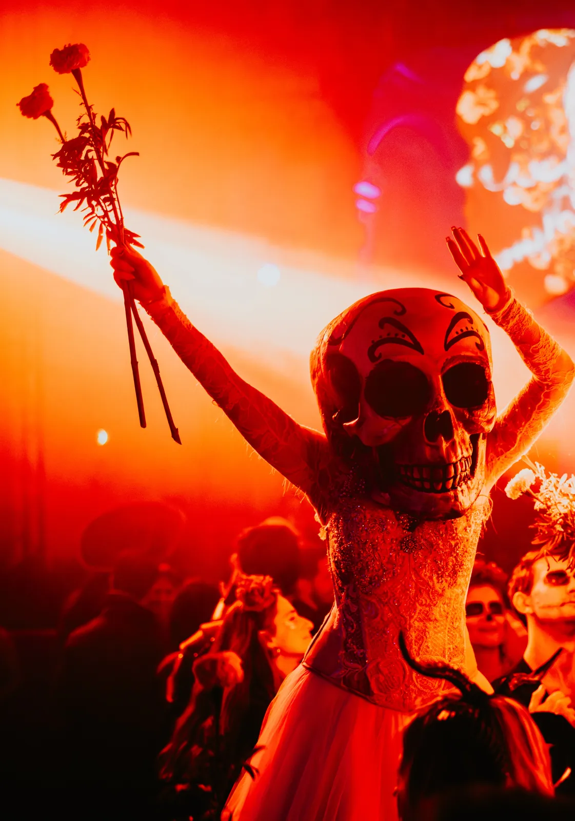 Performer in a sugar skull mask among the crowd
